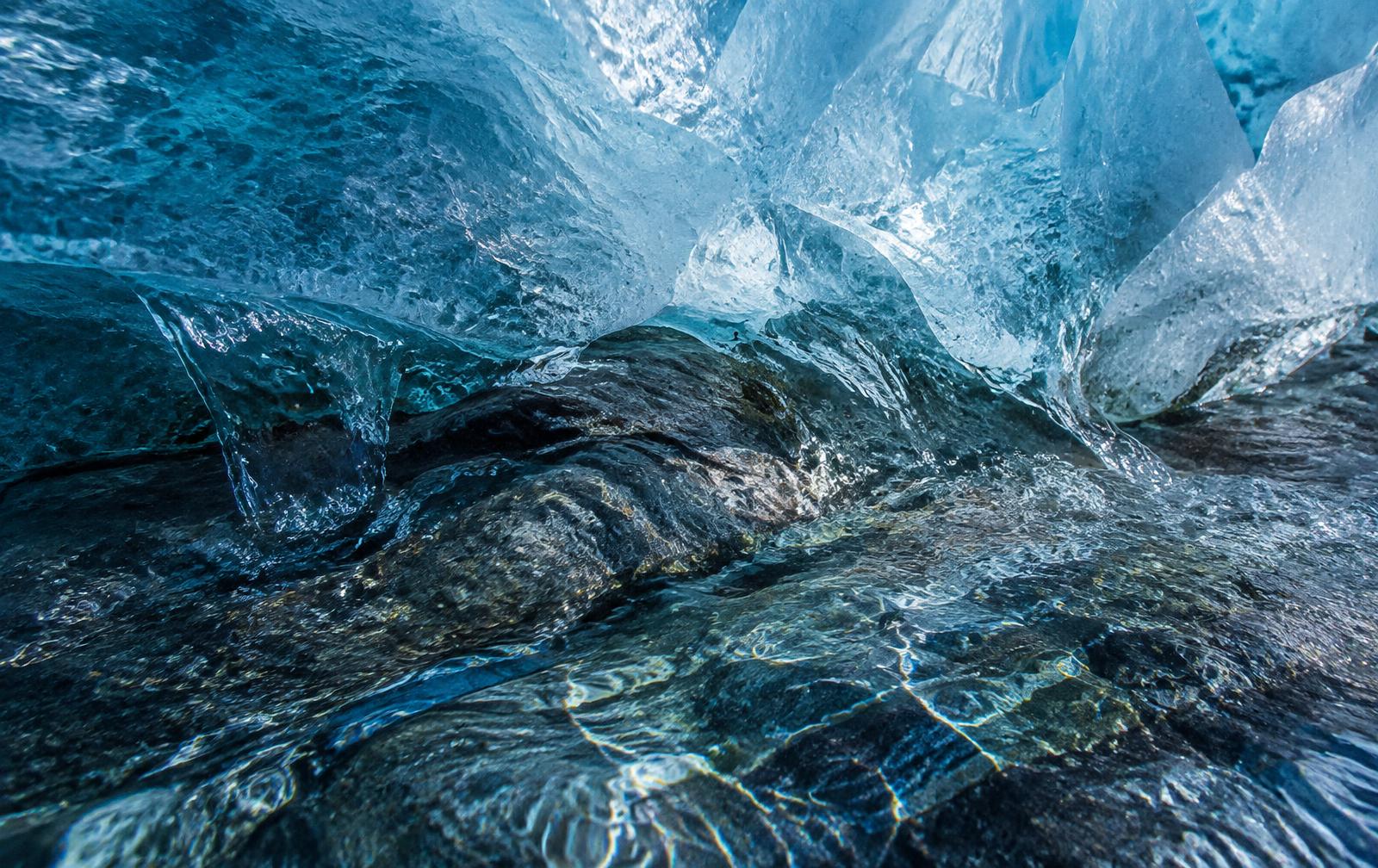 Glacier ice melting into clear spring water over ancient rock